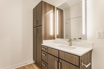 A bathroom with a sink, mirror, and wooden cabinets